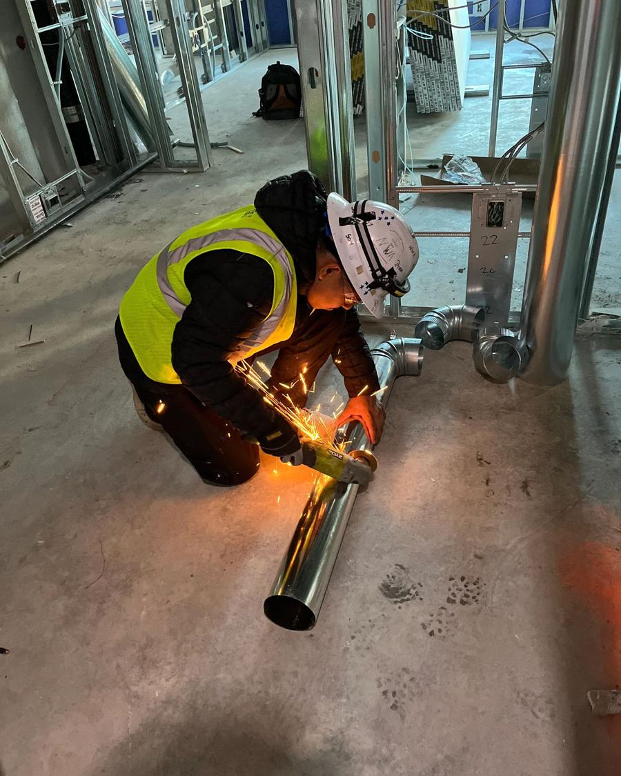 Crew member cutting pipe on a new construction site