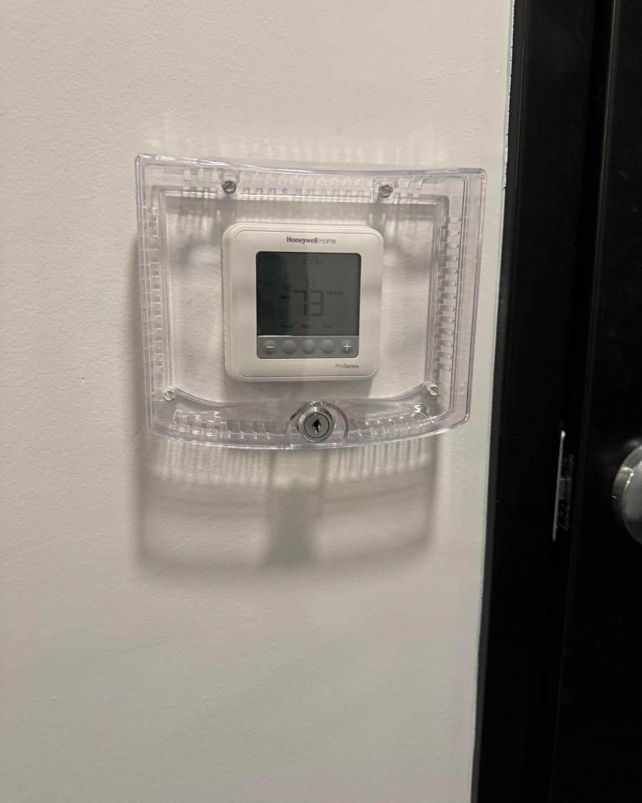 Thermostat with a protective cover on a hallway wall