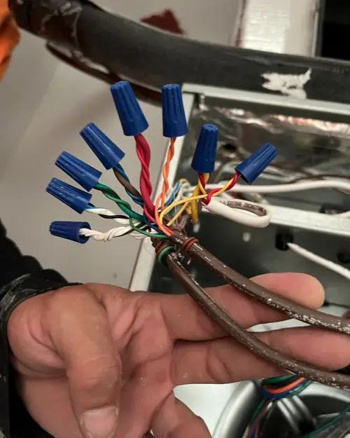 Hand holding thermostat control wiring